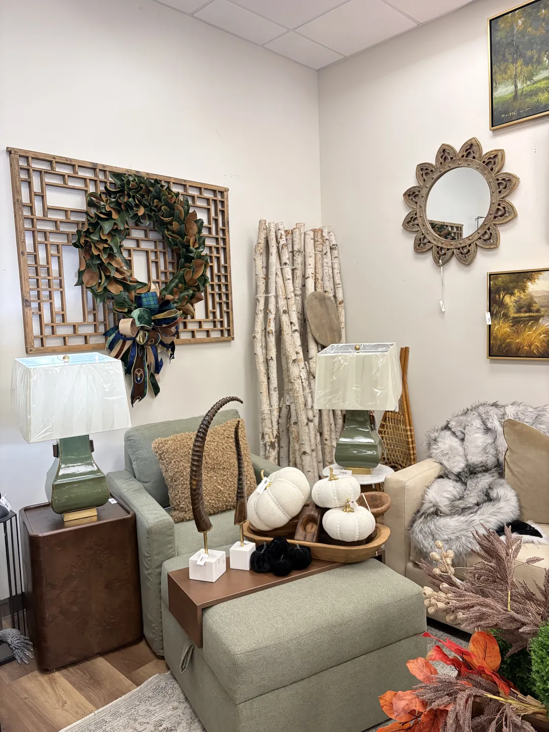 A finished corner: sage armchair and ottoman, green lamps, white pumpkins and a magnolia wreath on a lattice screen