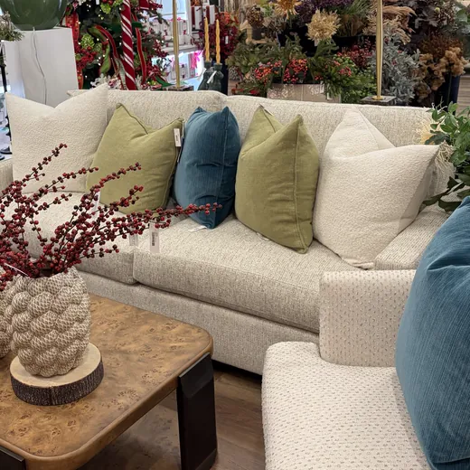 A cream sofa with green and blue pillows