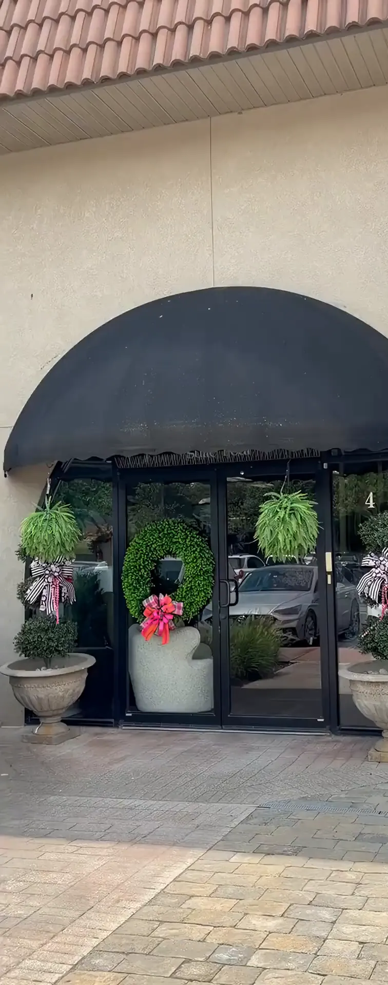 The arched black awning over the front door, with topiaries on either side