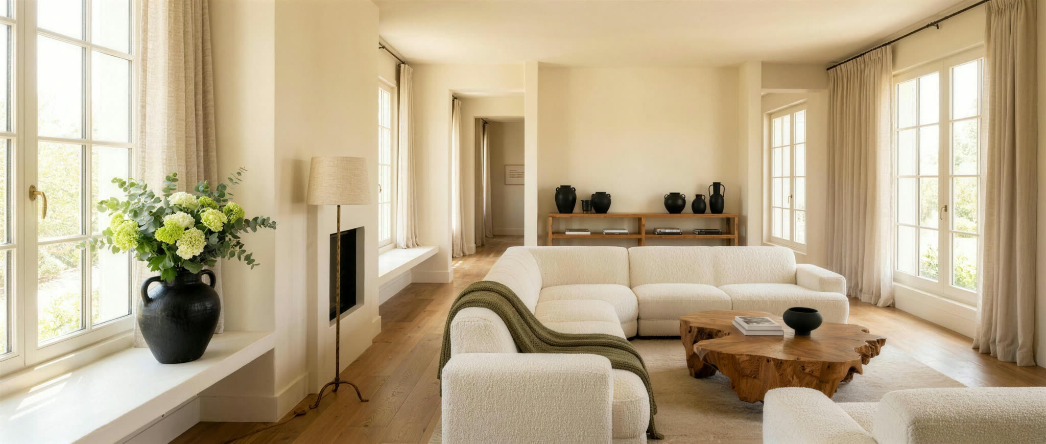 AI-rendered concept living room in Avenue's palette — ivory boucle sectional, burl coffee table, black and gold accents